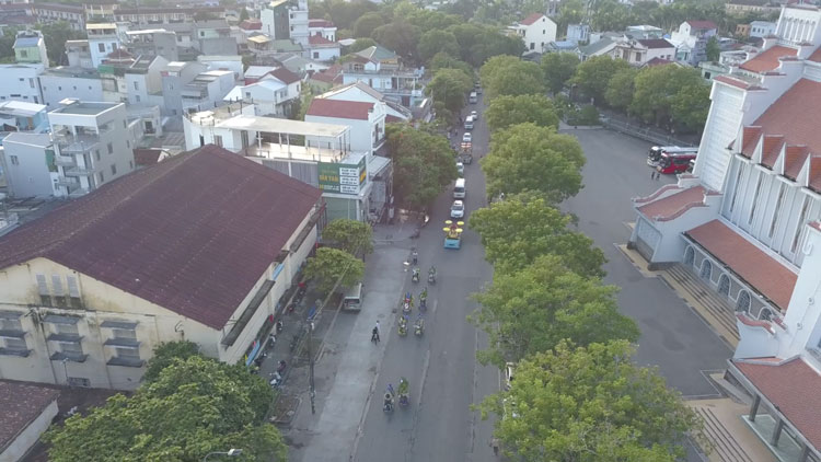 Picture from the drone where you can see Vietnamese Cyclo drivers are carrying flowers. Behind them, there is a car with a coffin.