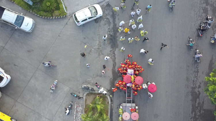 Fotografie pořízená z dronu zachycující rodinu a mnichy, kteří kráčejí za rakví.