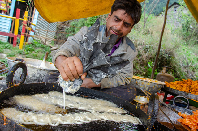 The way how Indian man is cooking Jalebi (Sweet and cheap dish from India). He is cooking it on the dirty pen where he is creating a particular shape.